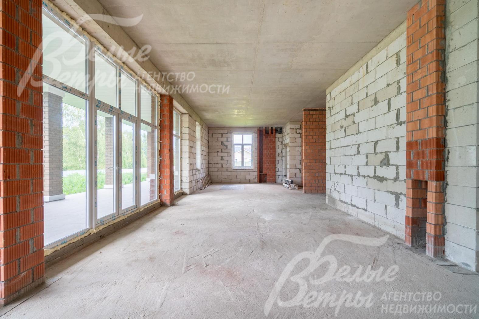 Просторное объединённое пространство гостиной, столовой и кухни наполнено естественным светом. В зоне гостиной предусмотрен камин (справа на фотографии)