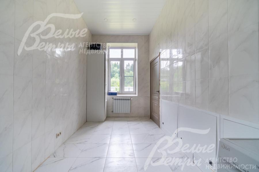 Постирочная на первом этаже отделана плиткой и панелями, установлена стиральная машина