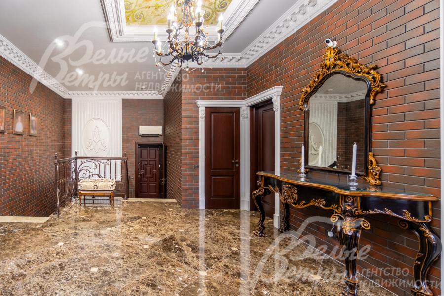 Просторный холл первого этажа со спуском на цокольный этаж. Центральный элемент интерьера - эксклюзивный итальянский консоль с зеркалом