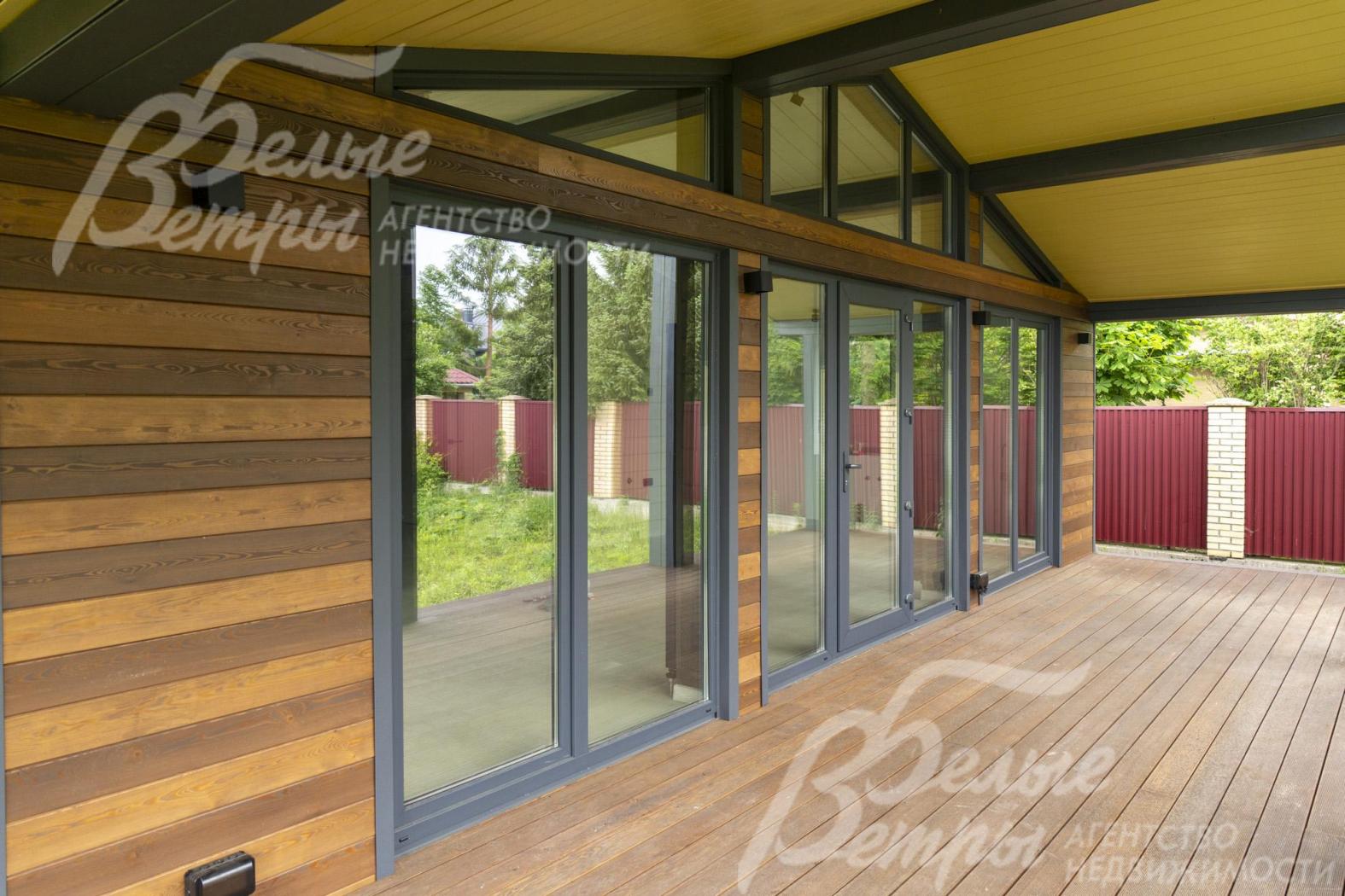 Выход на крытую террасу через дверь со стеклянными вставками из кухни-гостиной