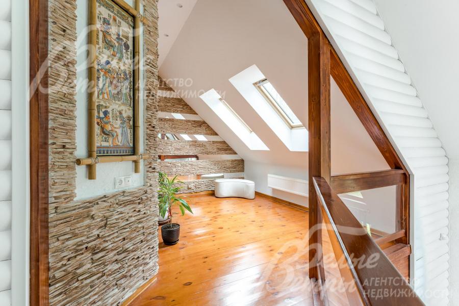 Холл-зимний сад на втором этаже с мансардными окнами и отделкой стен декоративными вставками из искусственного камня