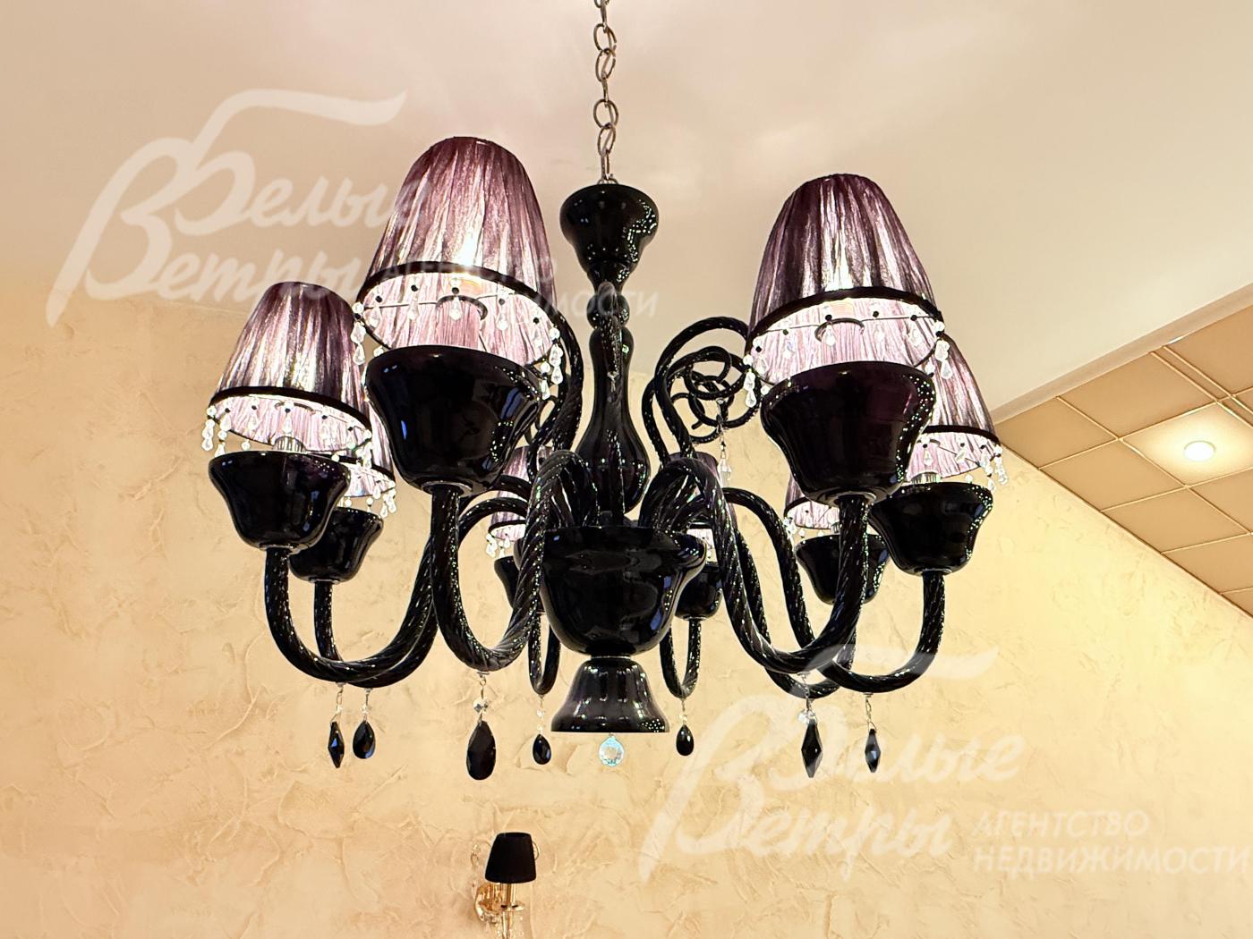 Также в каминном зале - подвесная люстра с элегантным изысканным дизайном выполнена в тёмной цветовой гамме, добавляющая интерьеру роскоши