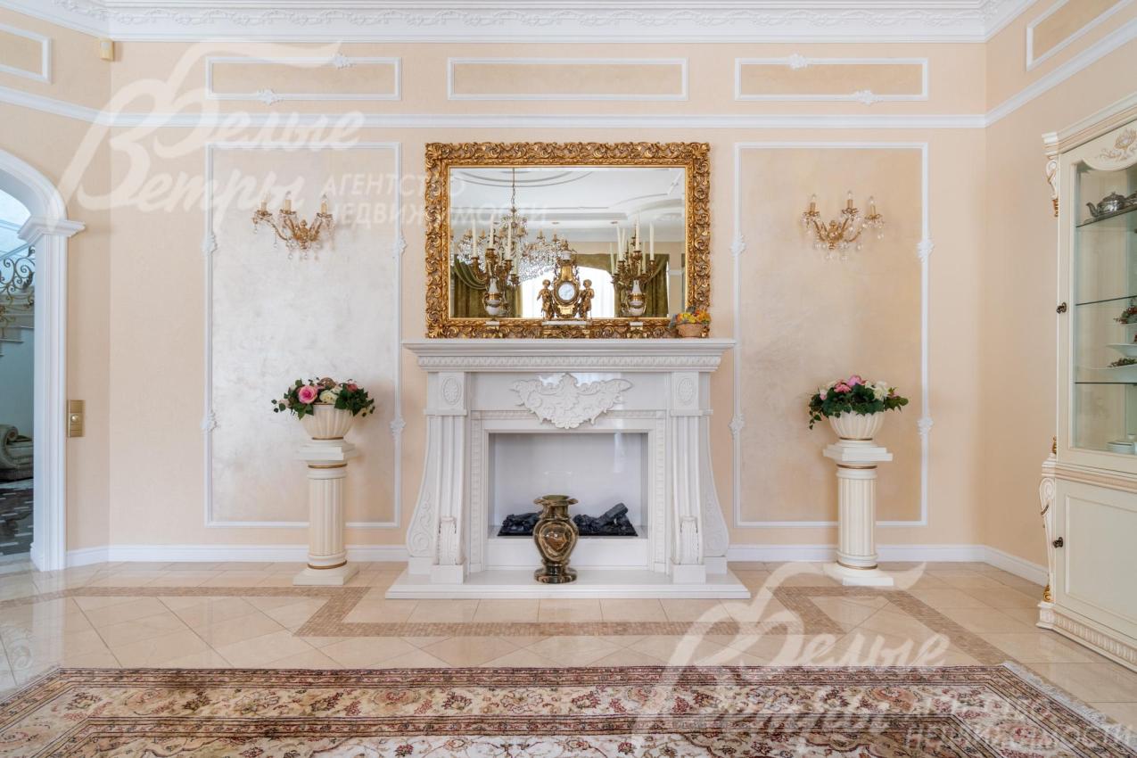Гостиную украшает каминный портал из белого мрамора с изящной лепниной и фигурными боковыми колоннами, над ним - крупное зеркало в золочёной раме