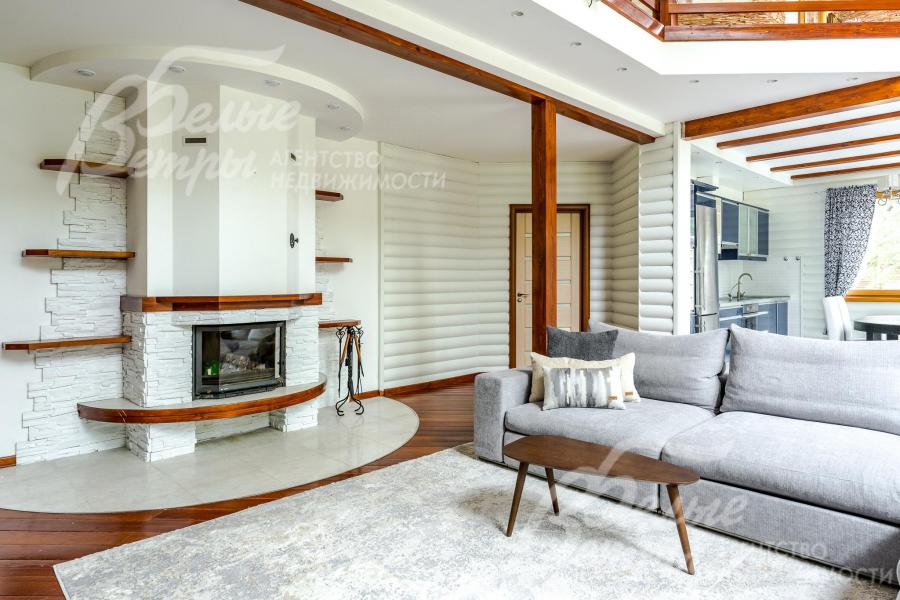 В гостиной стоит дровяной камин. Отделка стен комбинированная - покраска, блок-хаус, искусственный камень
