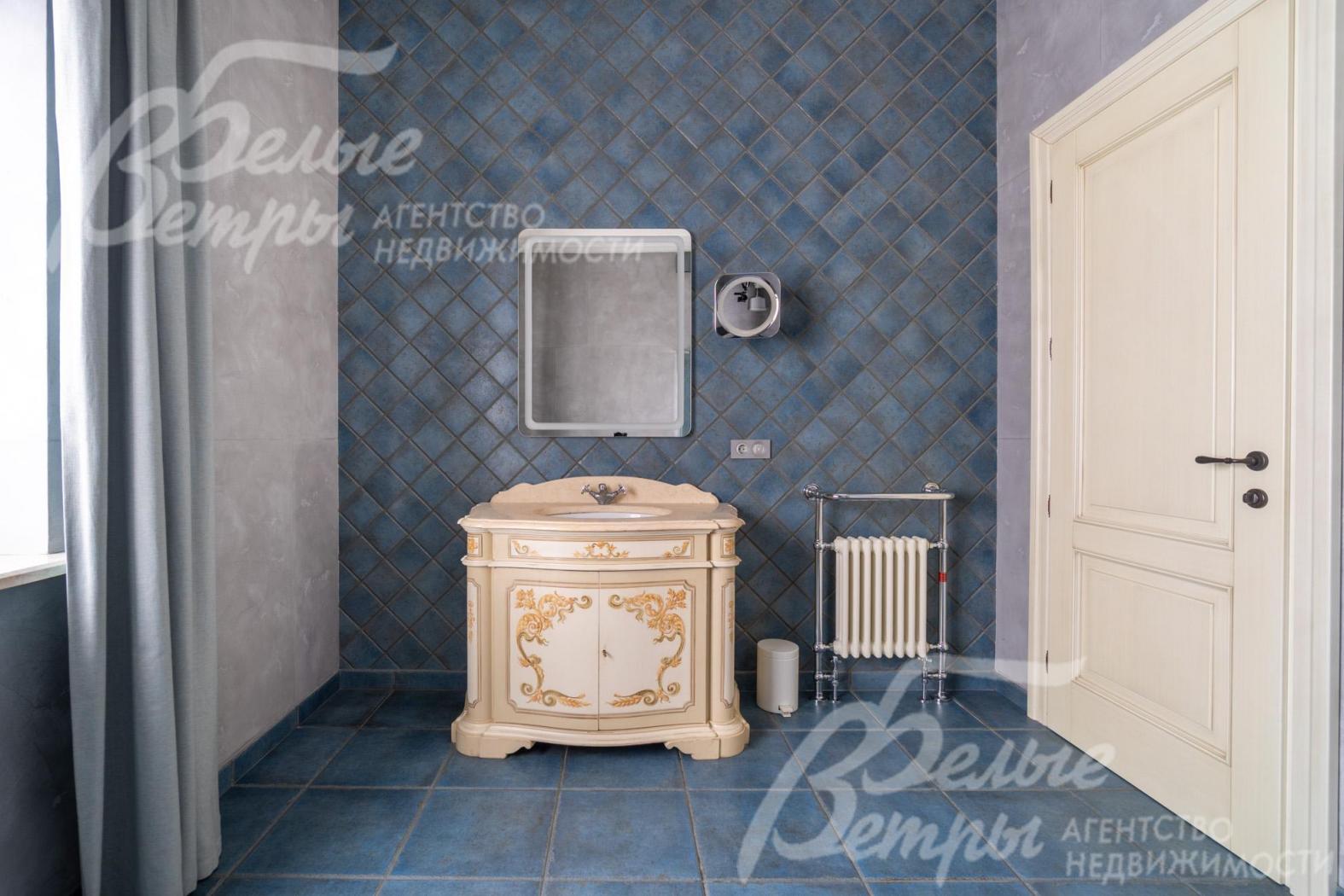 Санузел на втором этаже. Акцентная стена выложена плиткой, продолжающей оформление пола. В центре - классическая тумба под раковину с изящной росписью