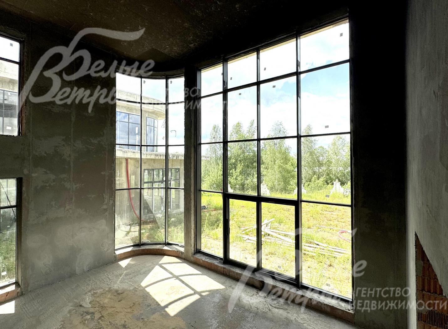 В гостиной - вертикальное остекление от пола до потолка с эркерным окном: открывается живописный вид на участок и в сторону озера