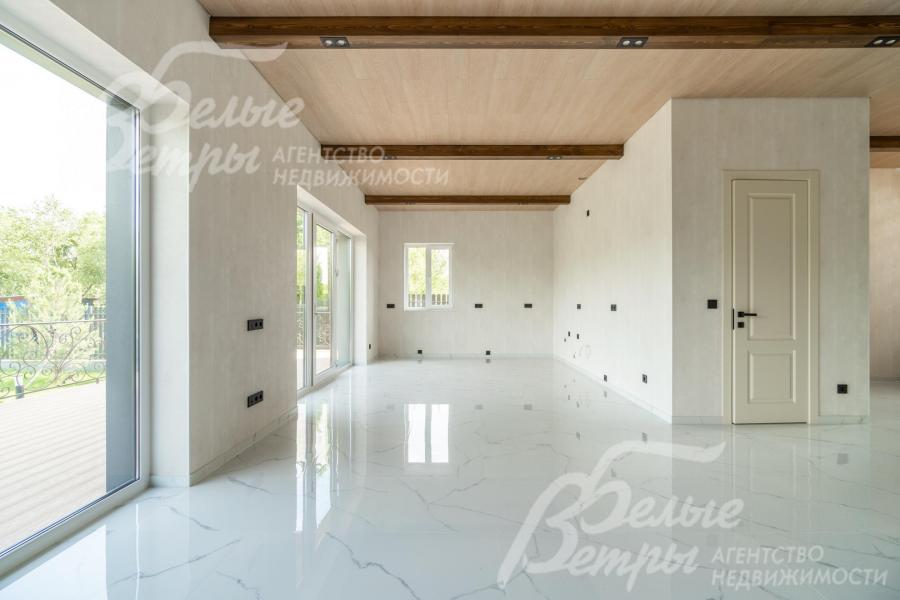 Единое пространство гостиной и кухни-столовой выглядит воздушно благодаря отделке в светлых тонах и панорамным окнам 