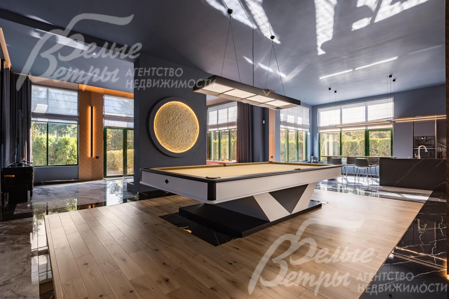 В гостиной находится двенадцатифутовый бильярдный стол от компании «Старт» с эффектным светильником-планетой