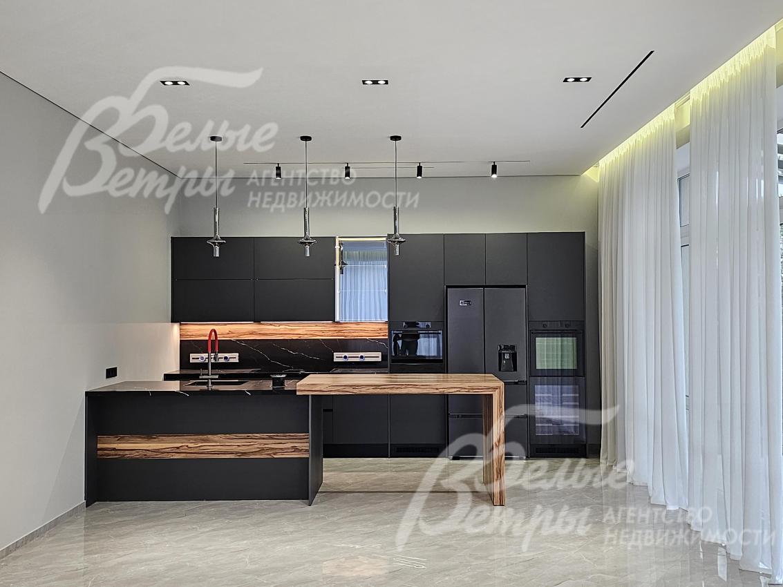 На кухне - стильный гарнитур с фасадами чёрного цвета, функциональным островом и полубарным столом