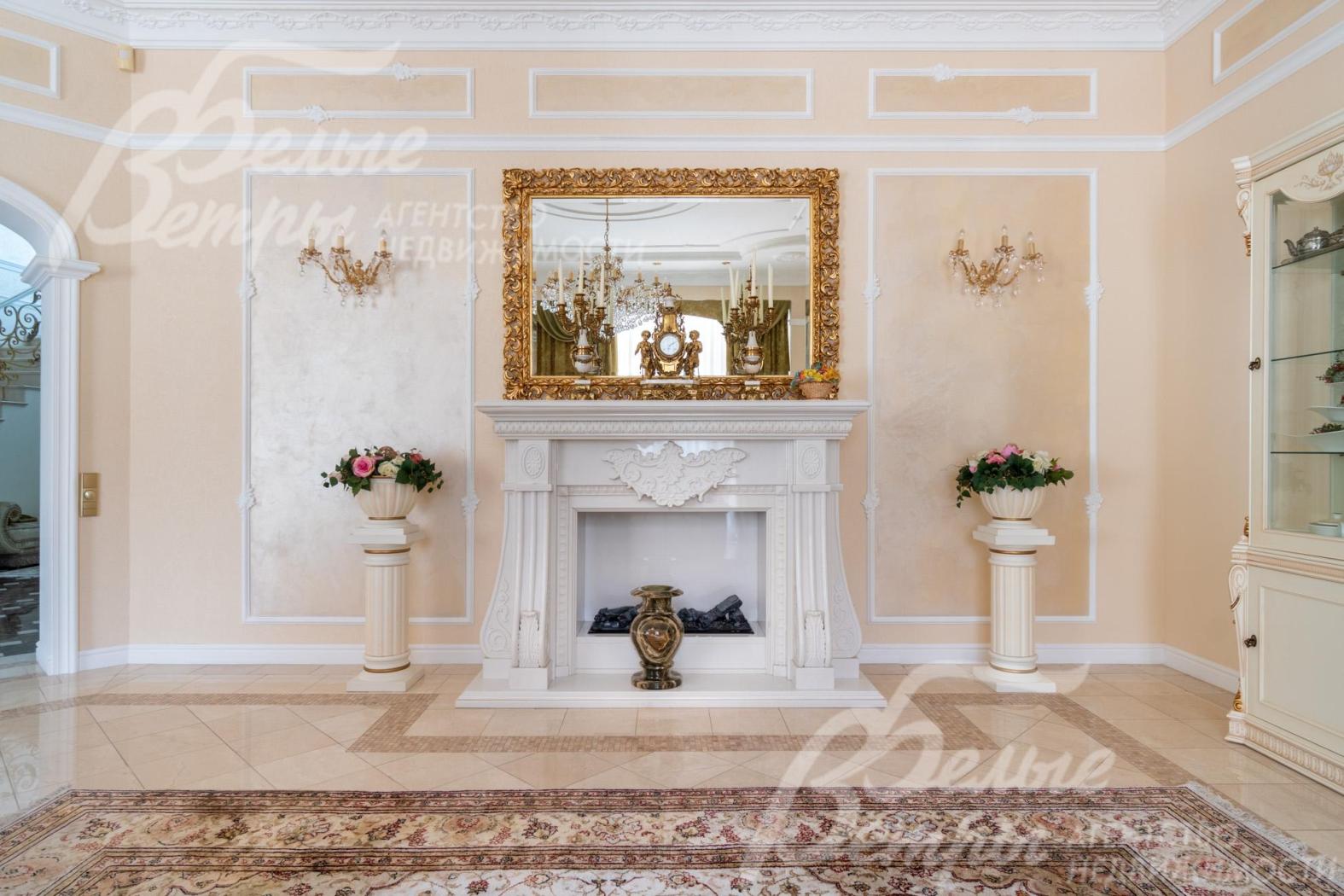Гостиную украшает каминный портал из белого мрамора с изящной лепниной и фигурными боковыми колоннами, над ним - крупное зеркало в золочёной раме