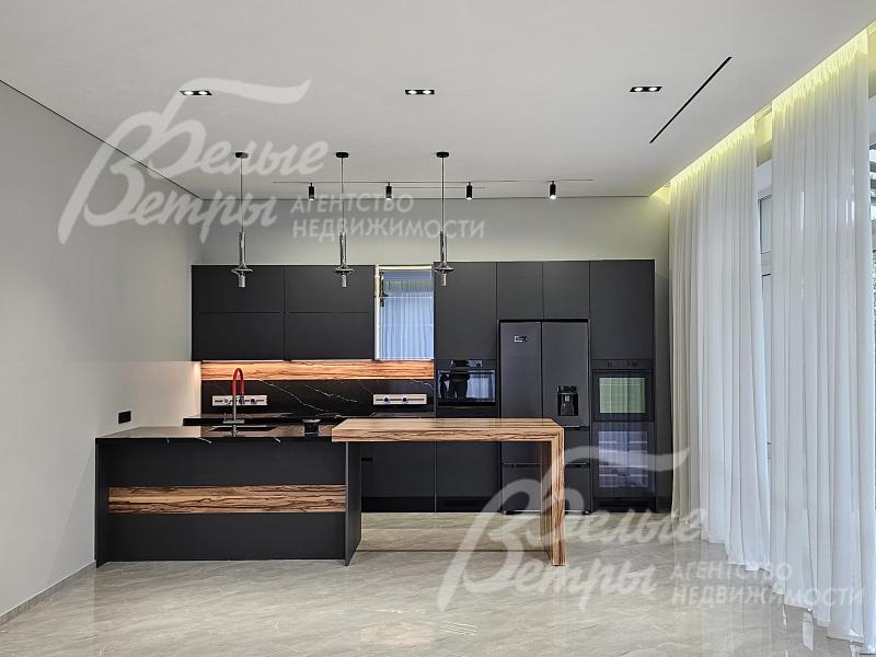 На кухне - стильный гарнитур с фасадами чёрного цвета, функциональным островом и полубарным столом