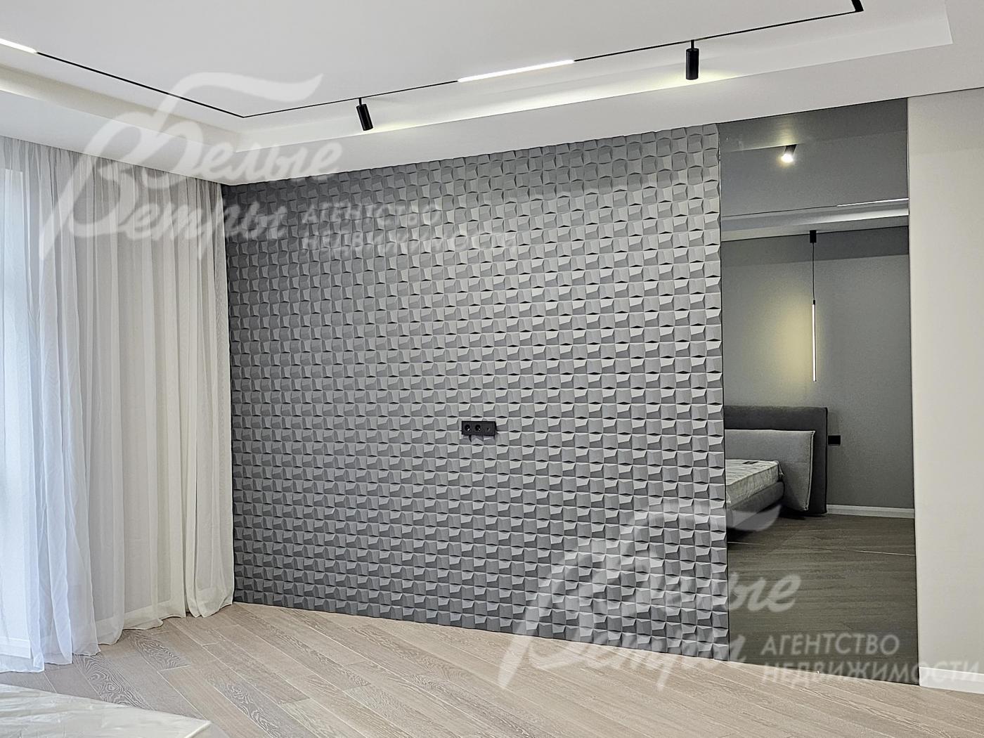 Декоративная перегородка с 3D-панелью разделяет спальную зону и гардеробную 