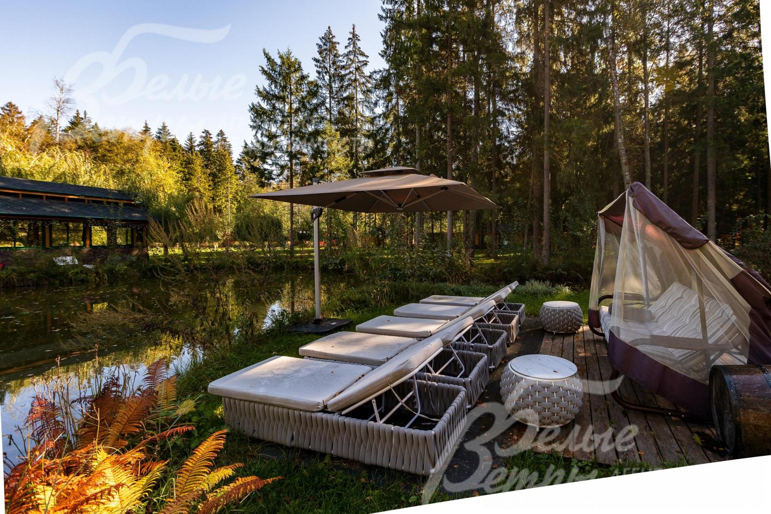 Возле пруда оборудована зона отдыха с шезлонгами. Через водоём перекинуты изящные мостики, завершающие облик пространства