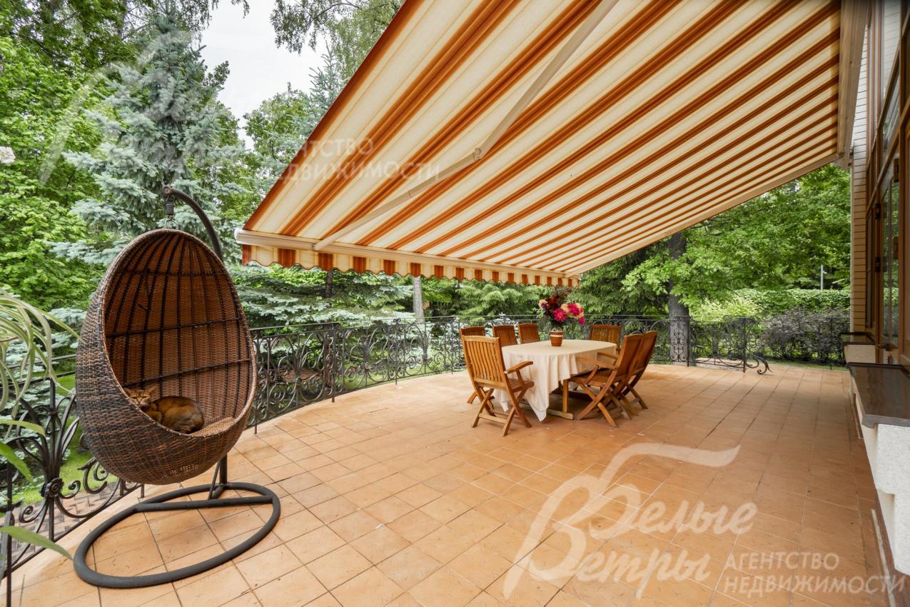 На террасе установлены качели-кокон и летняя обеденная группа