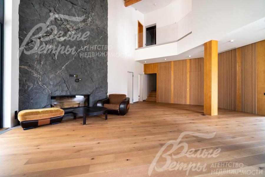 Гостиную украшает камин, обрамлённый фактурным каменным порталом на всю высоту помещения