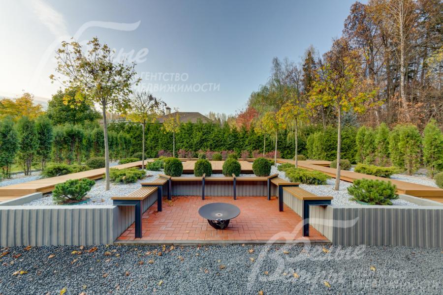 Зона для костра со скамейками вокруг и садом из декоративных растений