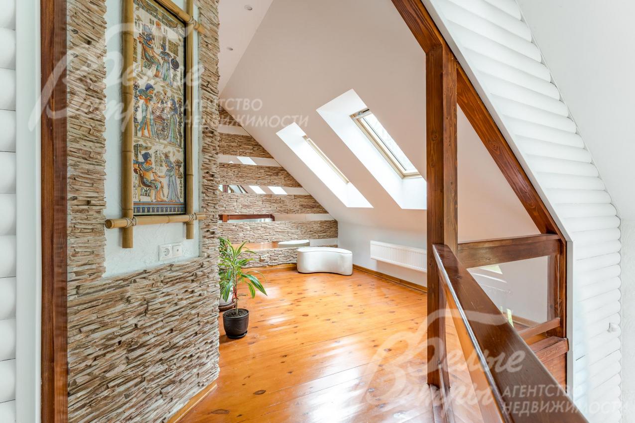 Холл-зимний сад на втором этаже с мансардными окнами и отделкой стен декоративными вставками из искусственного камня