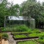 На участке организована садовая зона с высокими грядками и теплицей