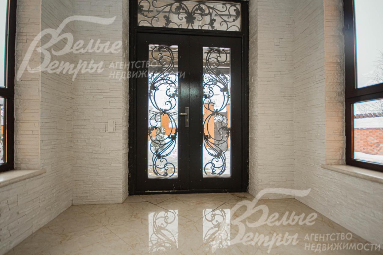 Красивая двустворчатая входная дверь со стеклом и художественной ковкой 