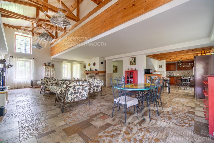 Объединённое пространство гостиной, столовой и кухни: на полу - мозаика из травертина с подогревом, на потолках из гипсокартона - массивные декоративные балки