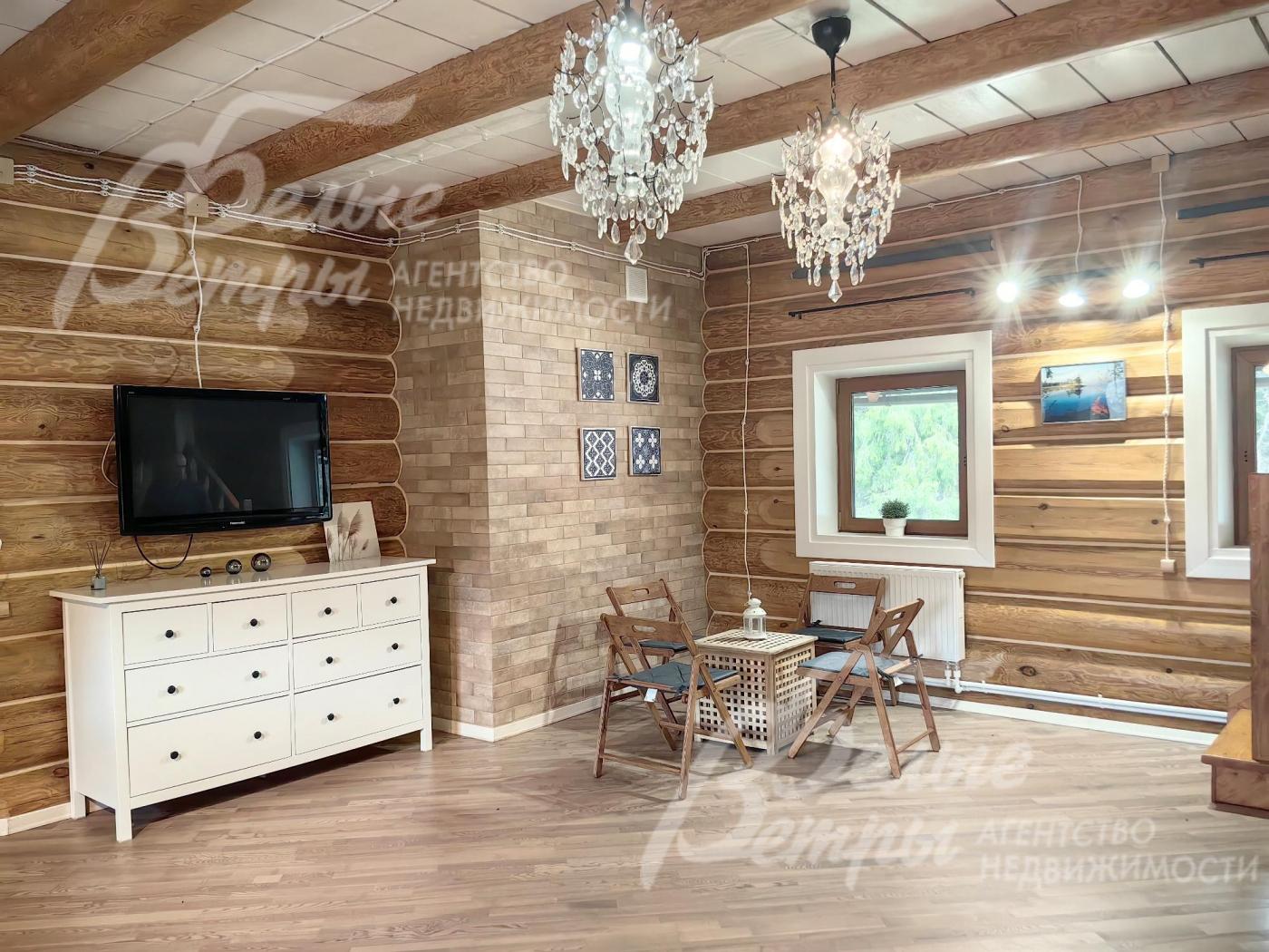 Стены и потолок в гостиной отделаны деревом, на полу ламинат.