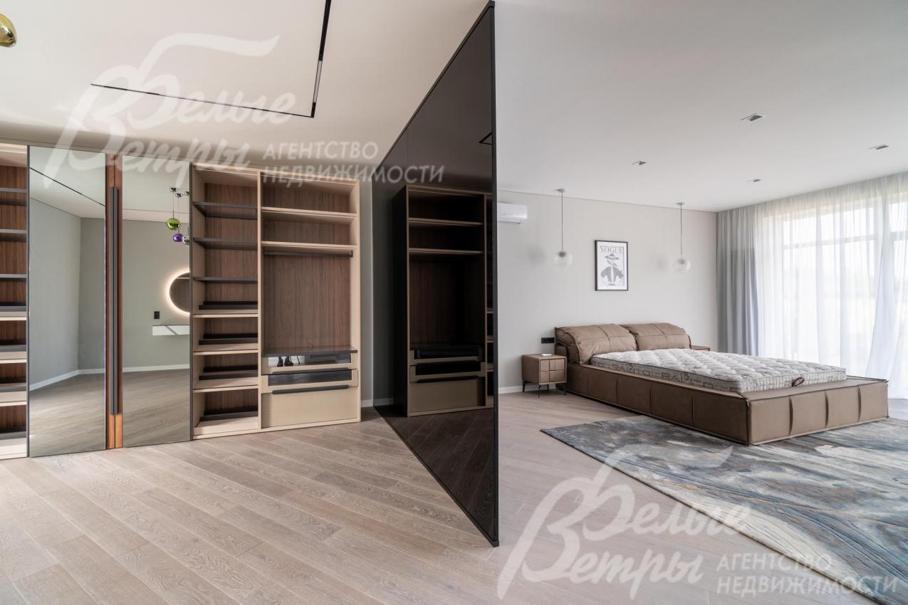 Гардеробная в мастер-спальне зонирована стеклянной тонированной перегородкой