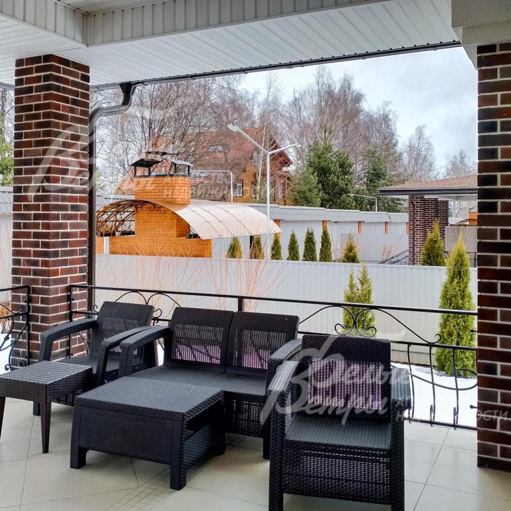 Крытая терраса с плетеной мебелью для отдыха.