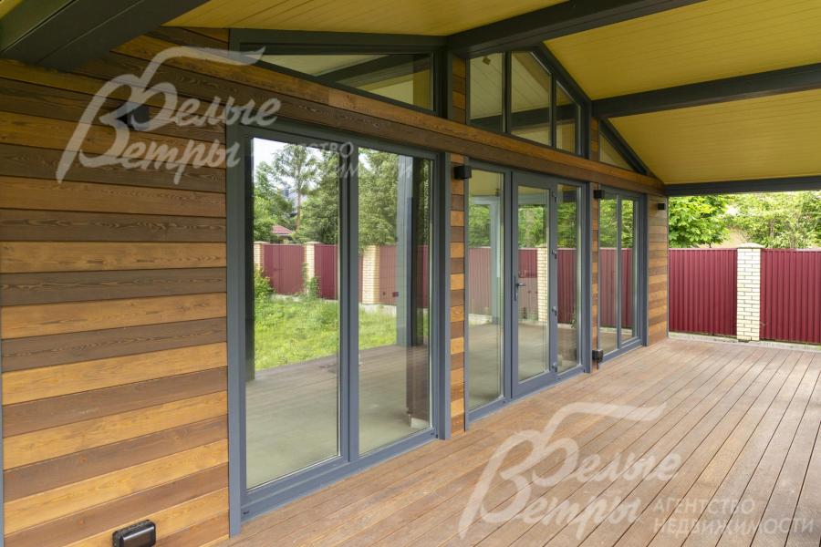 Выход на крытую террасу через дверь со стеклянными вставками из кухни-гостиной