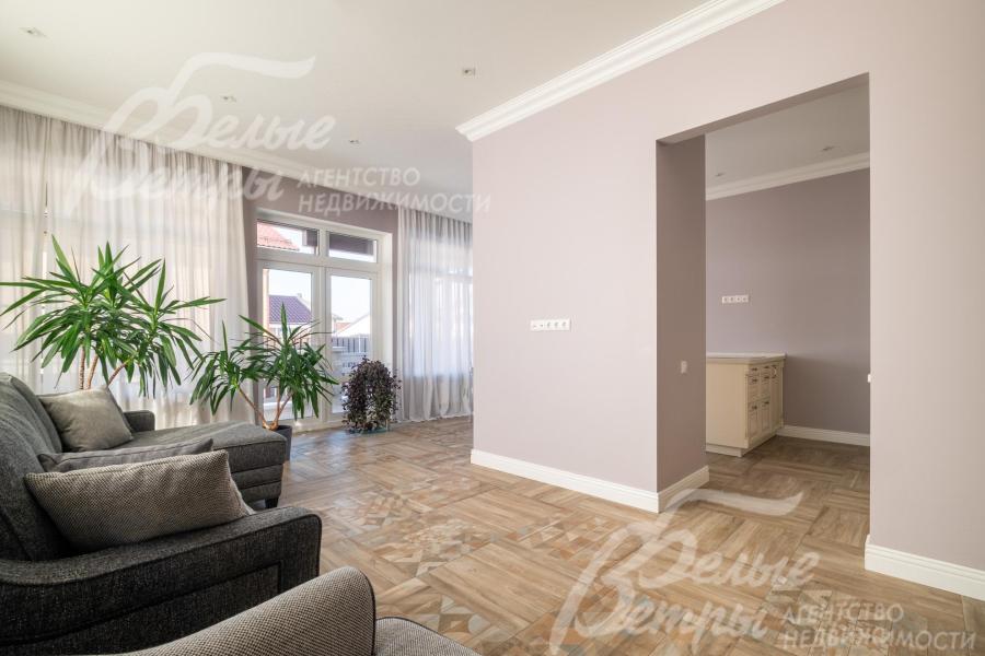 Зоны гостиной и кухни-столовой разделяет перегородка с порталом, на полу в этих помещениях уложен керамогранит с водяными полами