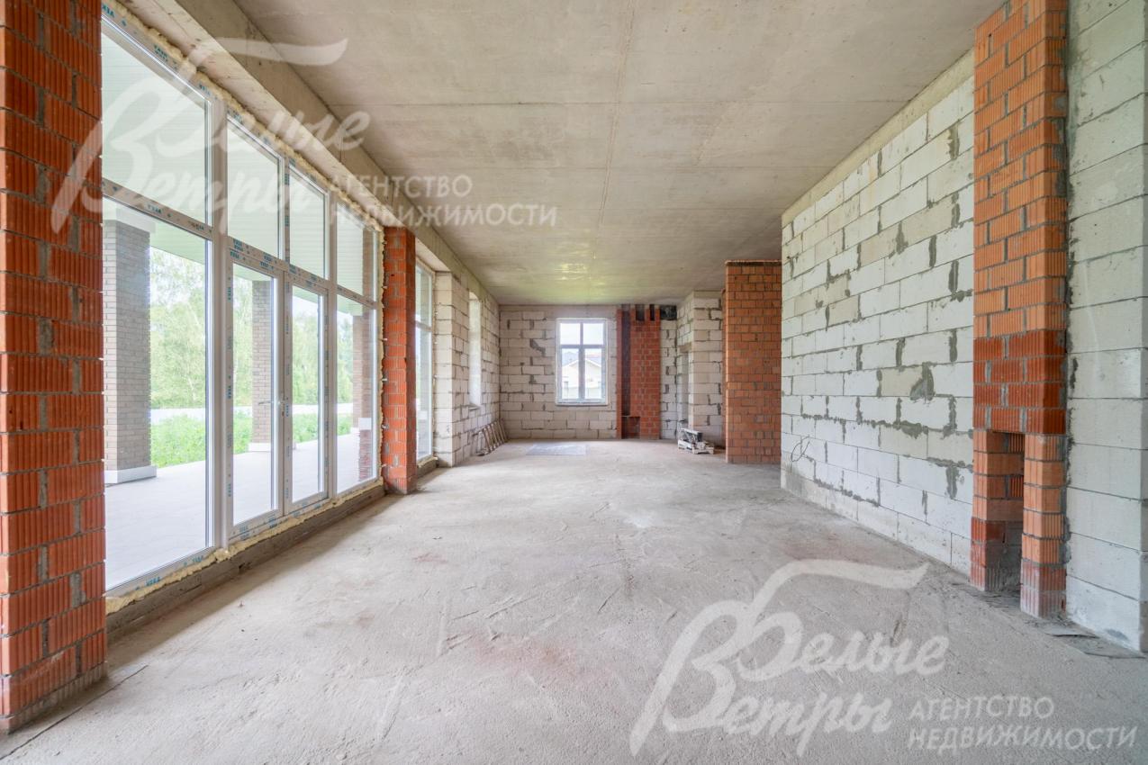 Просторное объединённое пространство гостиной, столовой и кухни наполнено естественным светом. В зоне гостиной предусмотрен камин (справа на фотографии)