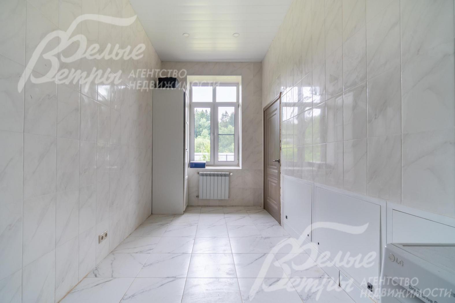 Постирочная на первом этаже отделана плиткой и панелями, установлена стиральная машина