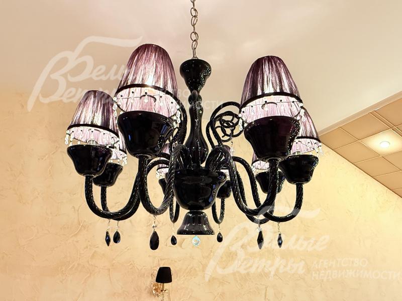 Также в каминном зале - подвесная люстра с элегантным изысканным дизайном выполнена в тёмной цветовой гамме, добавляющая интерьеру роскоши