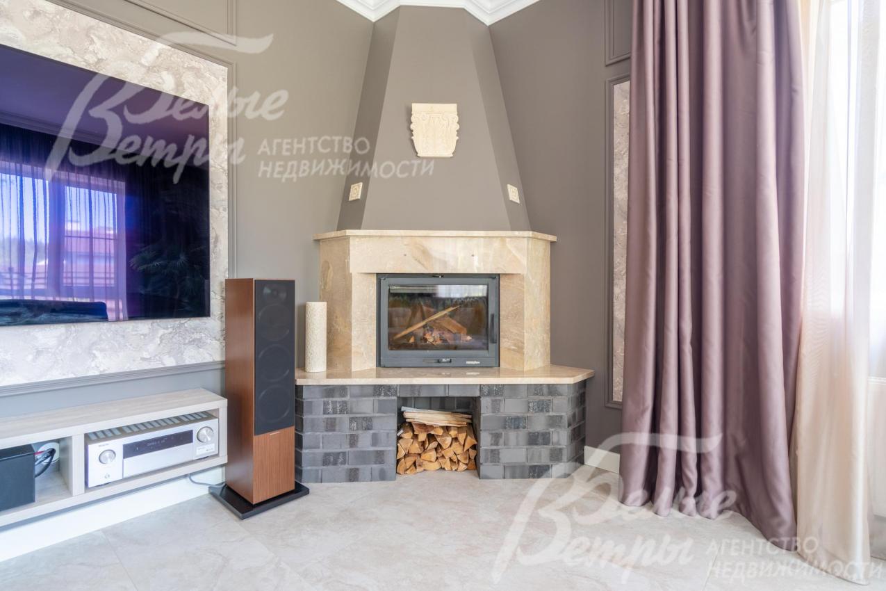 Гостиную украшает дровяной камин, отделанный мрамором и клинкерной плиткой