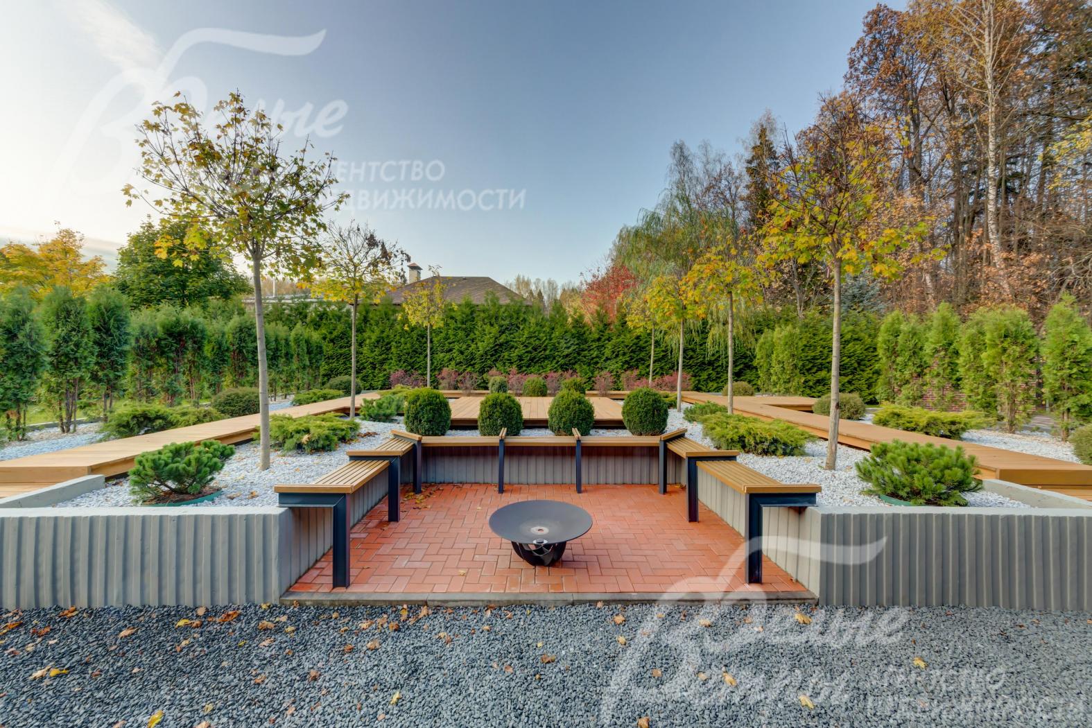 Зона для костра со скамейками вокруг и садом из декоративных растений