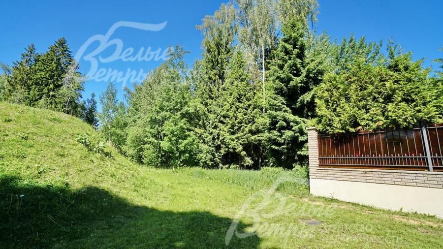 С одной стороны участка кованый забор на кирпичных столбах