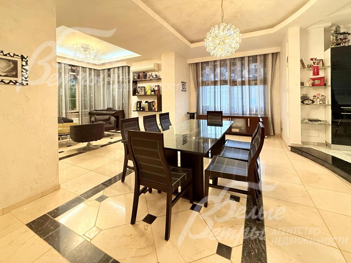 Обеденная группа со столом с тонированной стеклянной столешницей и стульями из тёмного дерева рассчитана на 8 персон