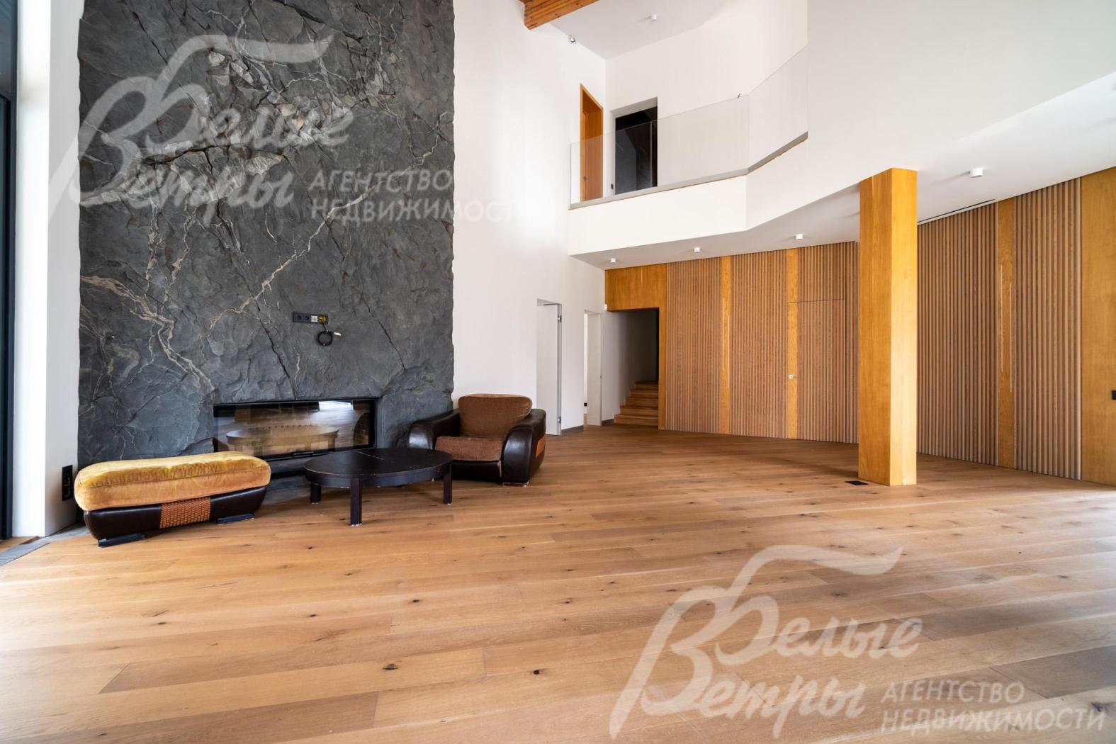 Гостиную украшает камин, обрамлённый фактурным каменным порталом на всю высоту помещения