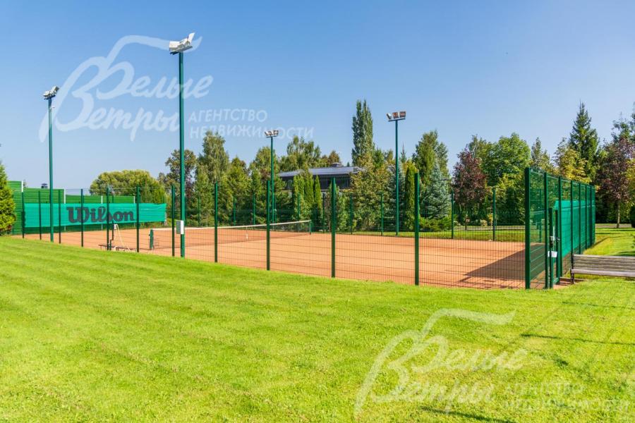 Теннисный корт с профессиональным покрытием и вечерним освещением.