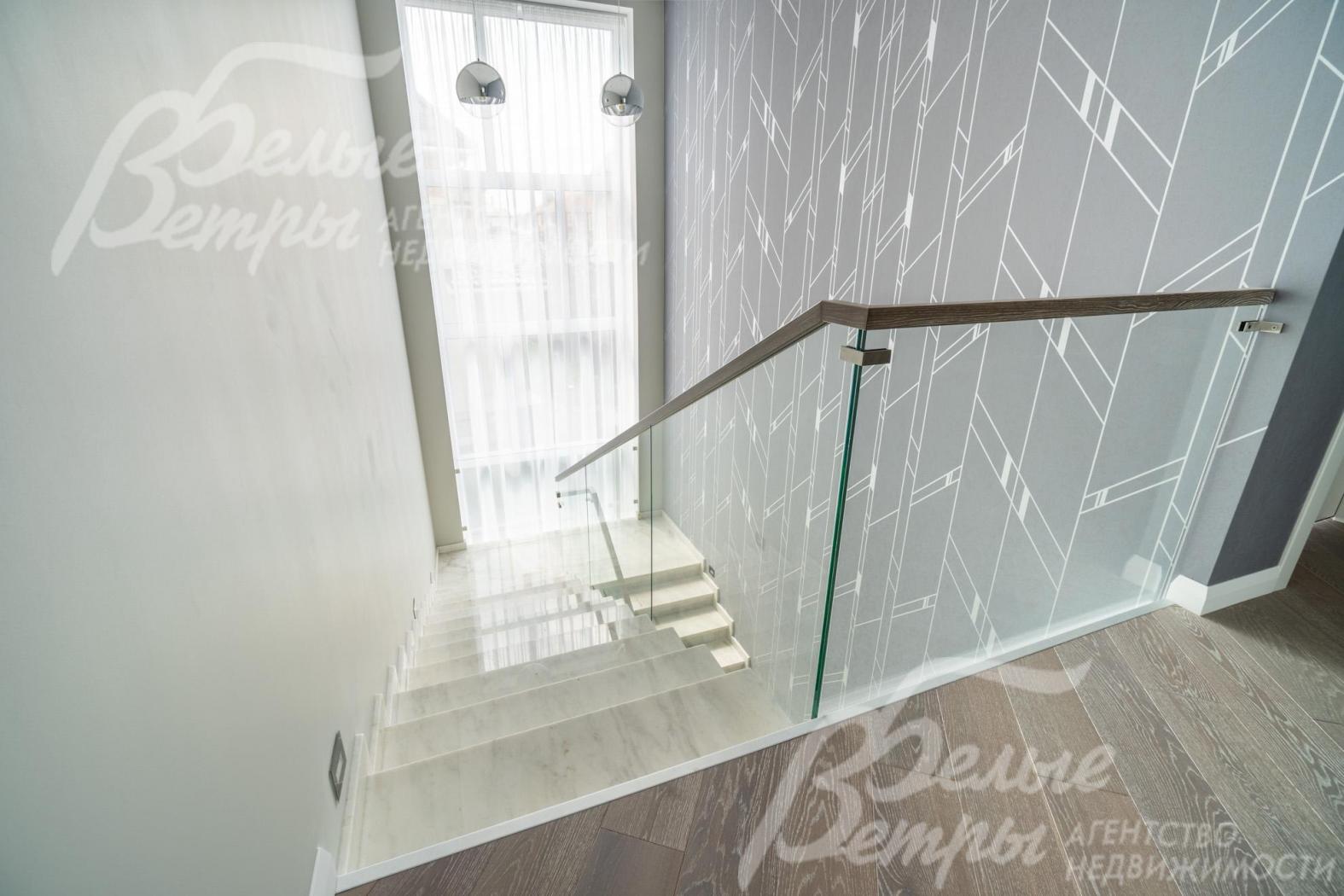 Большое окно за лестничным проёмом наполняет оба этажа дома естественным светом