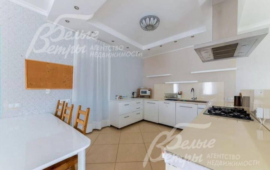 На кухне установлен гарнитур белого цвета со встроенной техникой