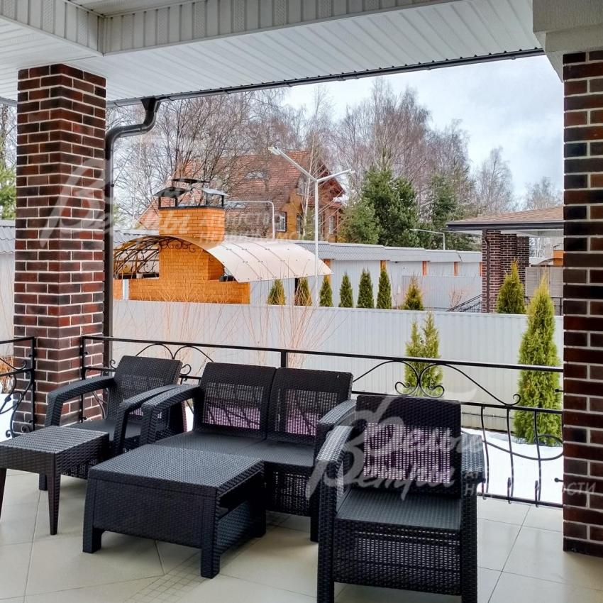 Крытая терраса с плетеной мебелью для отдыха.