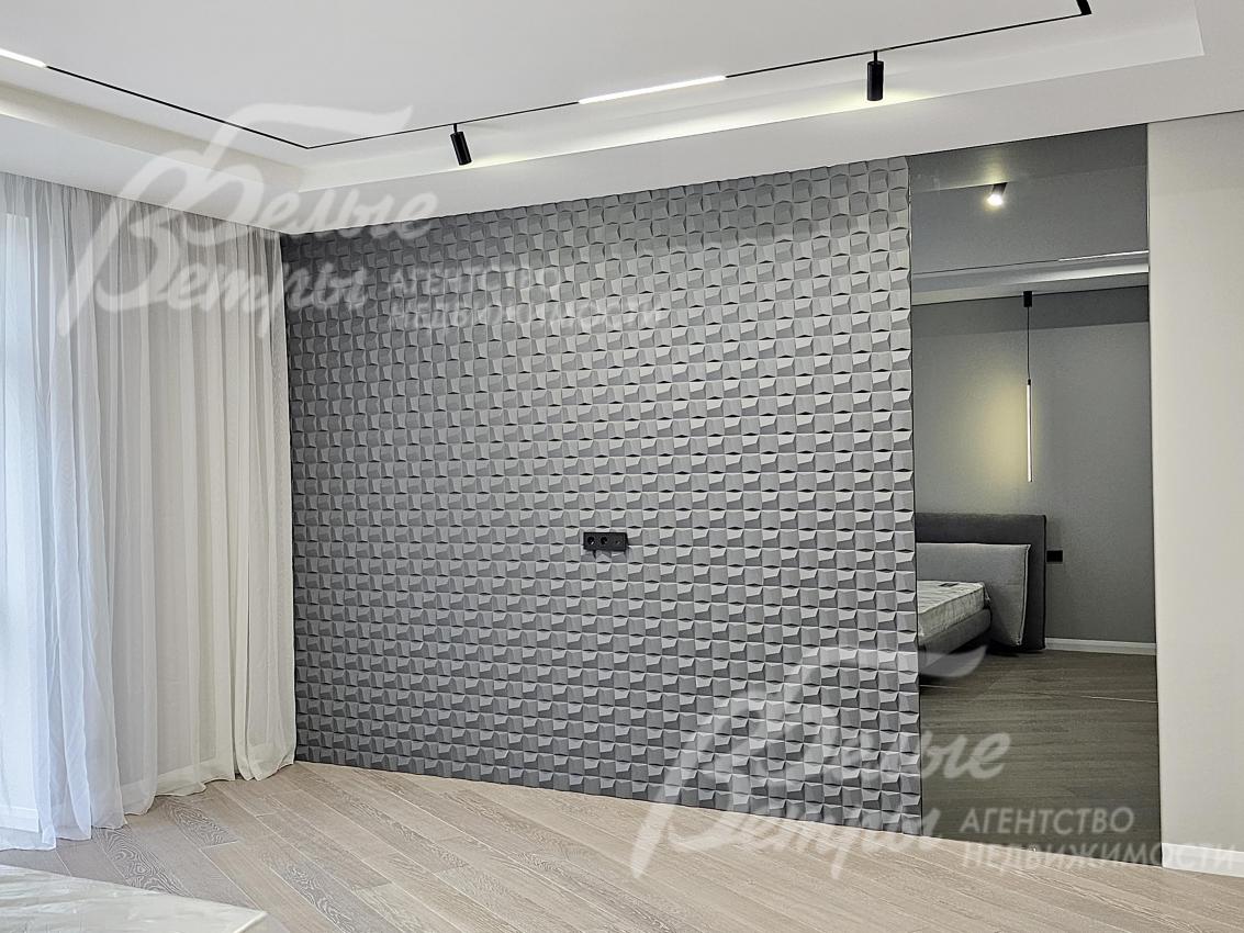 Декоративная перегородка с 3D-панелью разделяет спальную зону и гардеробную 