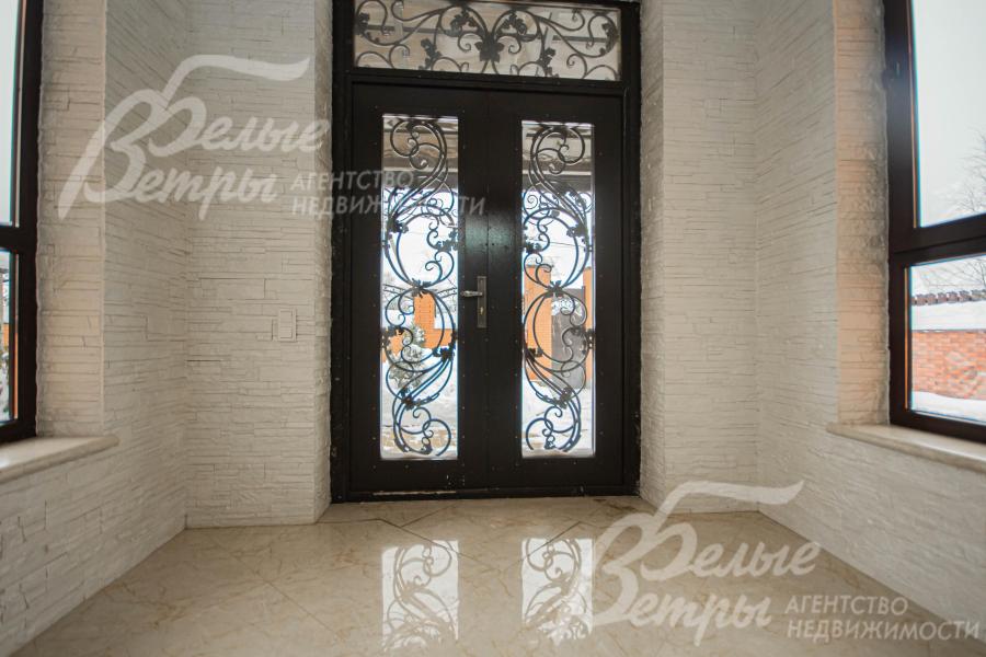 Красивая двустворчатая входная дверь со стеклом и художественной ковкой 